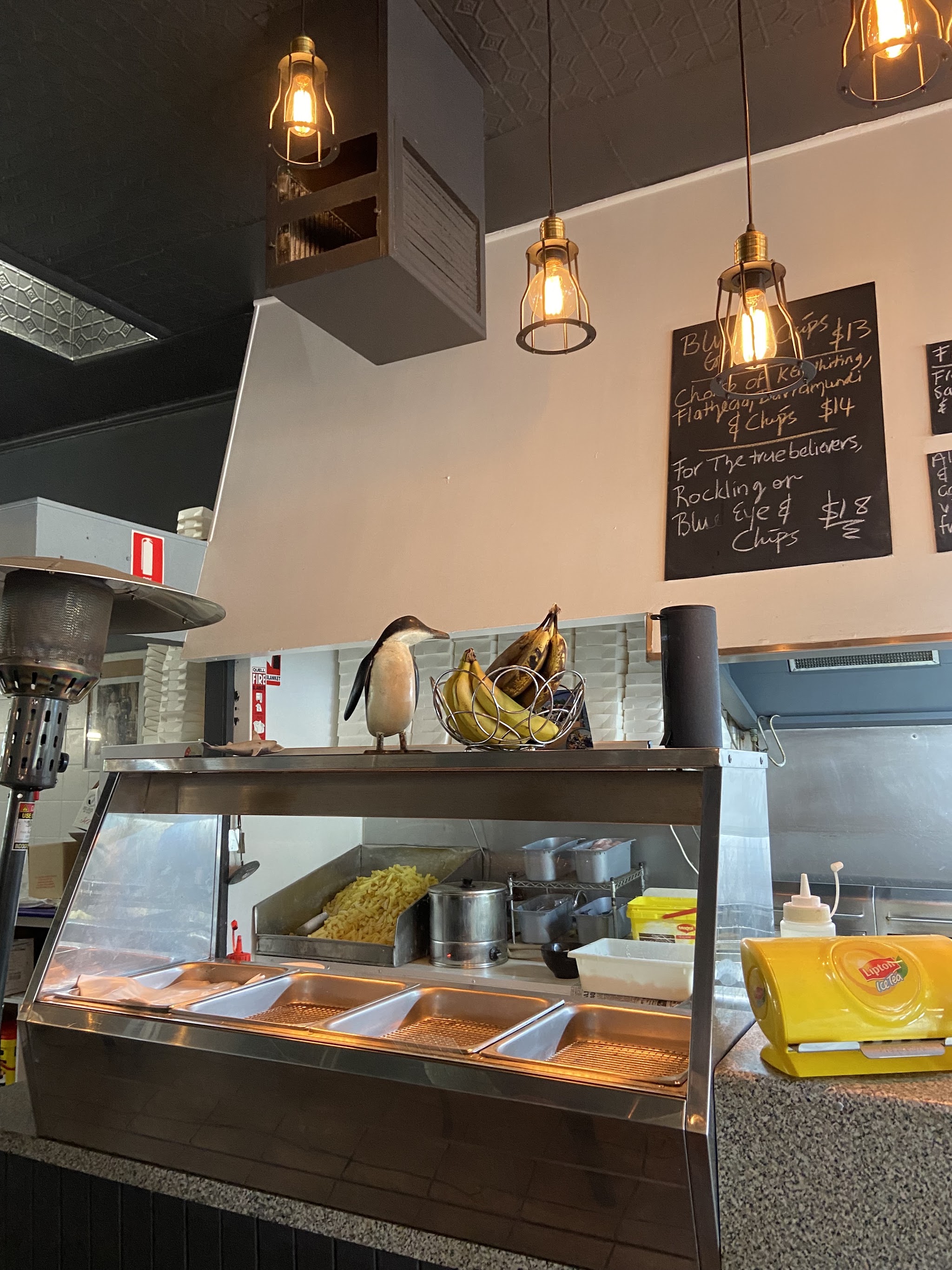 The hot cabinet and fryer station inside the shop, with the specials board above