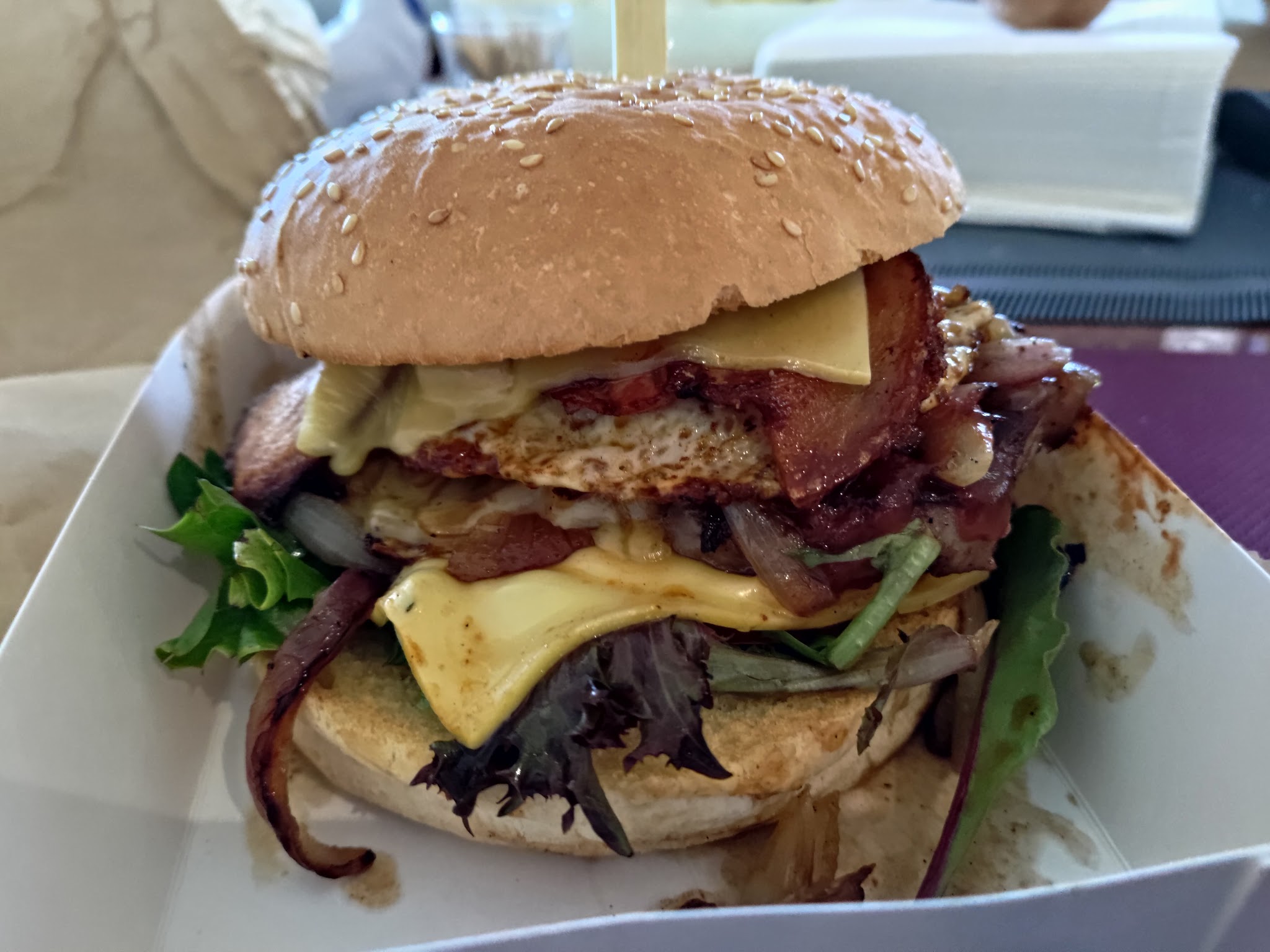 Burger with bacon, fried egg, cheese and salad on a sesame bun